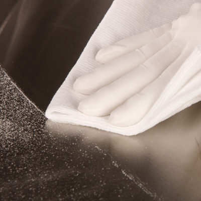 close up of white glove using white towel to wipe off black table top