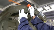 close of of white gloves cleaning under hood of car