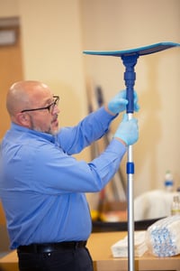 man in light blue button shirt holding a mop