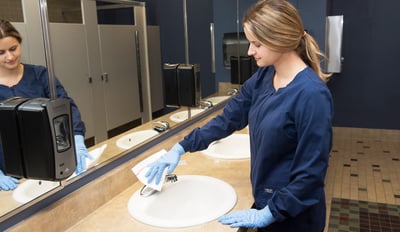 Woman cleaning public bathroom sink