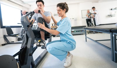 Man on exercise bike with fitness trainer