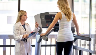 fit woman on treadmill speaking with trainer